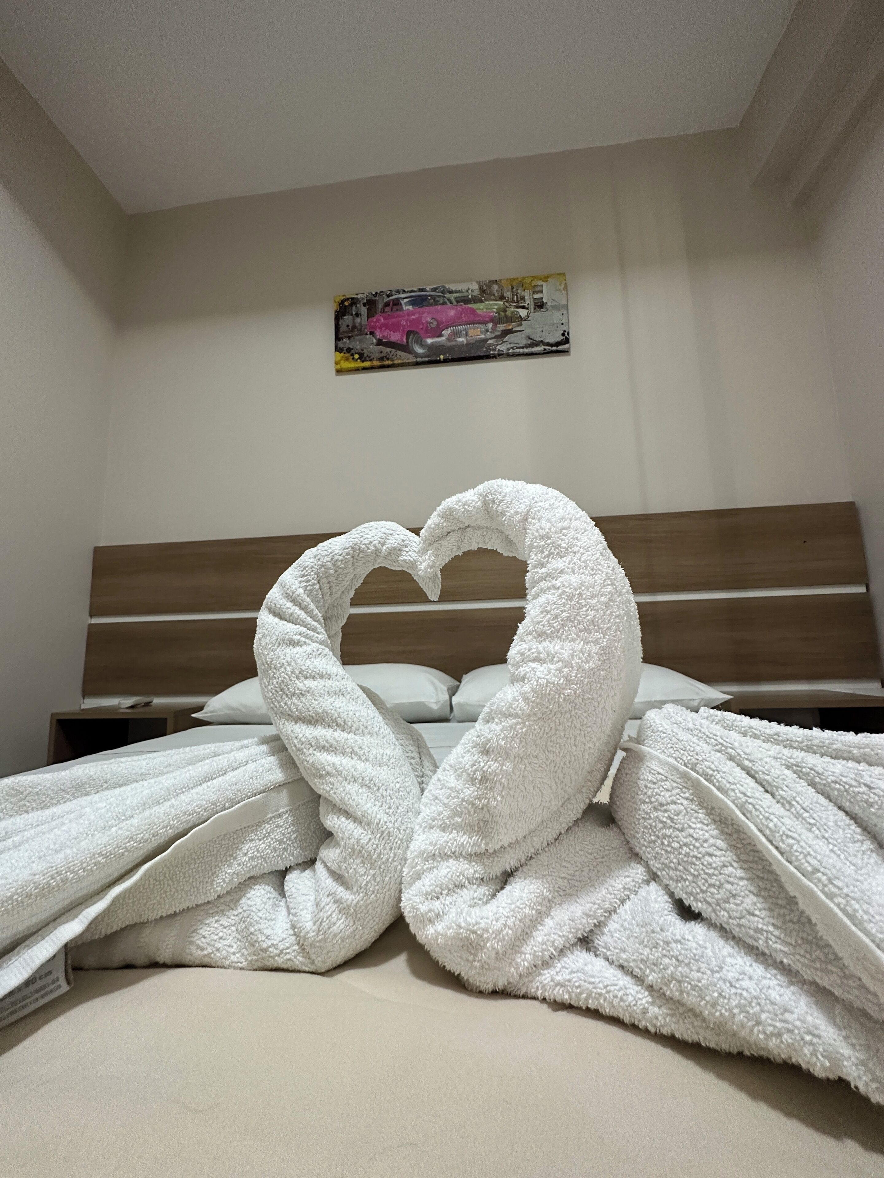 A bed with white towels arranged in a heart shape.