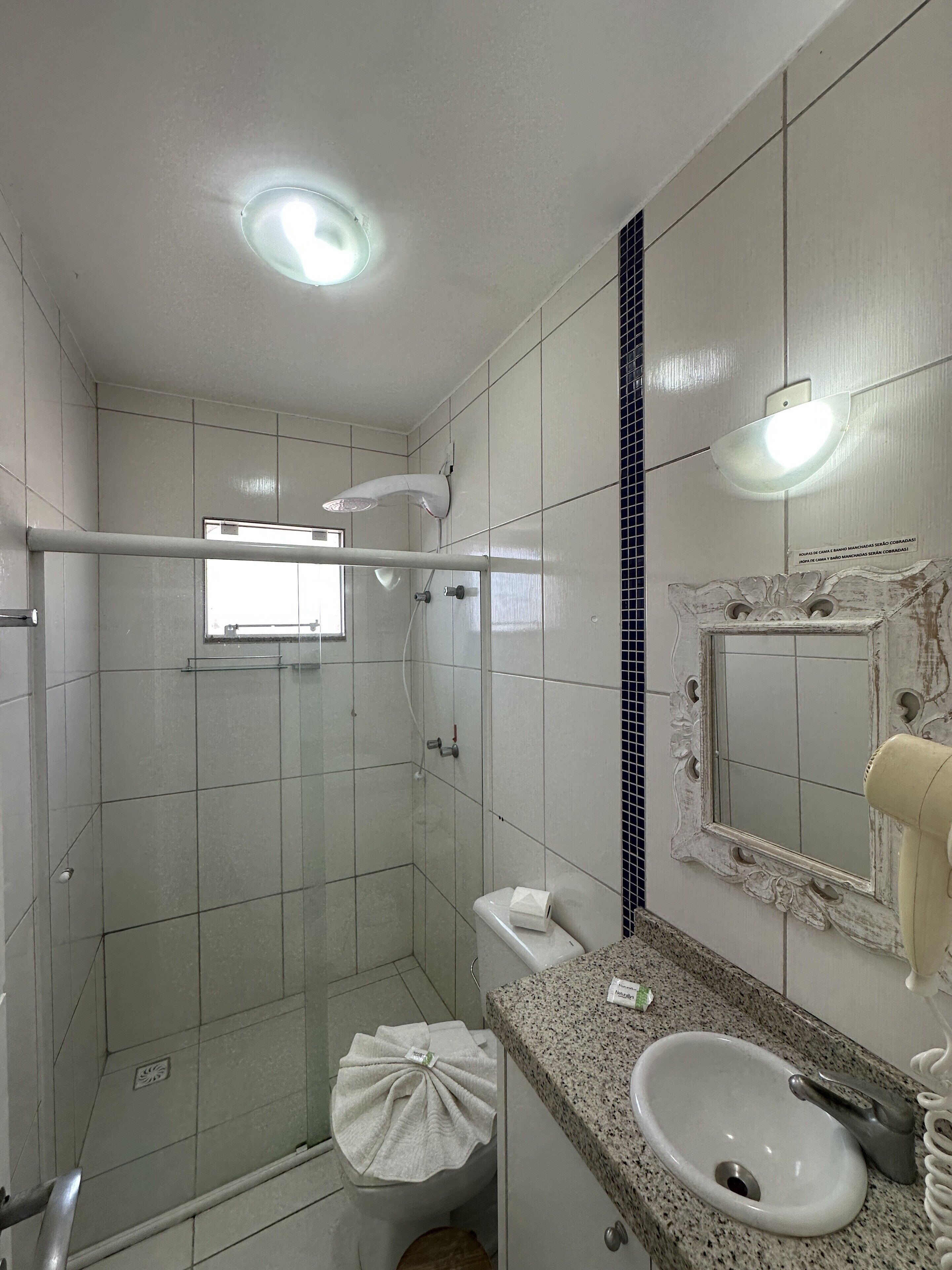 Une salle de bain équipée d’une douche, de toilettes, d’un lavabo et d’un miroir avec un cadre décoratif.