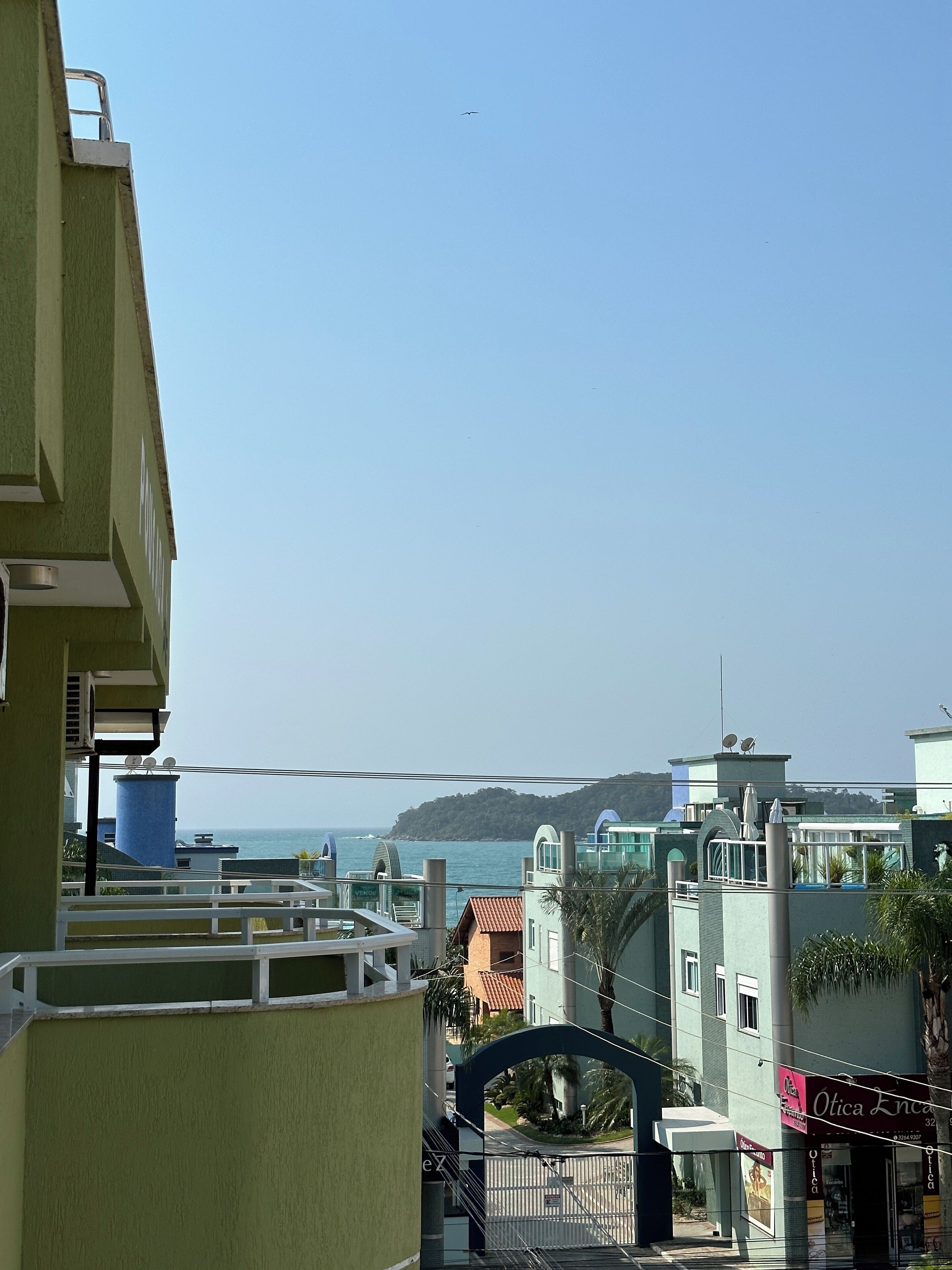 Un bâtiment situé sur la côte, offrant une vue sur la mer, doté d’un balcon et d’un réservoir d’eau bleu.