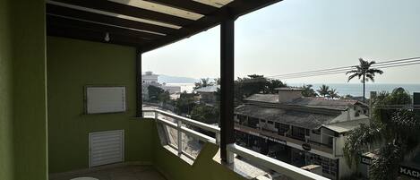 A balcony with a view of a cityscape, a white table, and a chair.