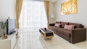 A modern living room with a brown sofa, a coffee table, a flat-screen TV, and a large window with curtains.