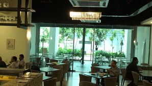 A restaurant with indoor seating, large windows, and a chandelier.