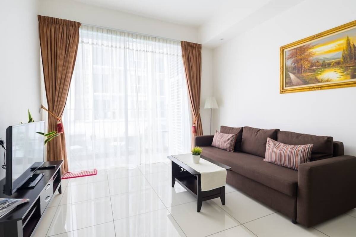 A modern living room with a brown sofa, a coffee table, a TV, and a painting on the wall.