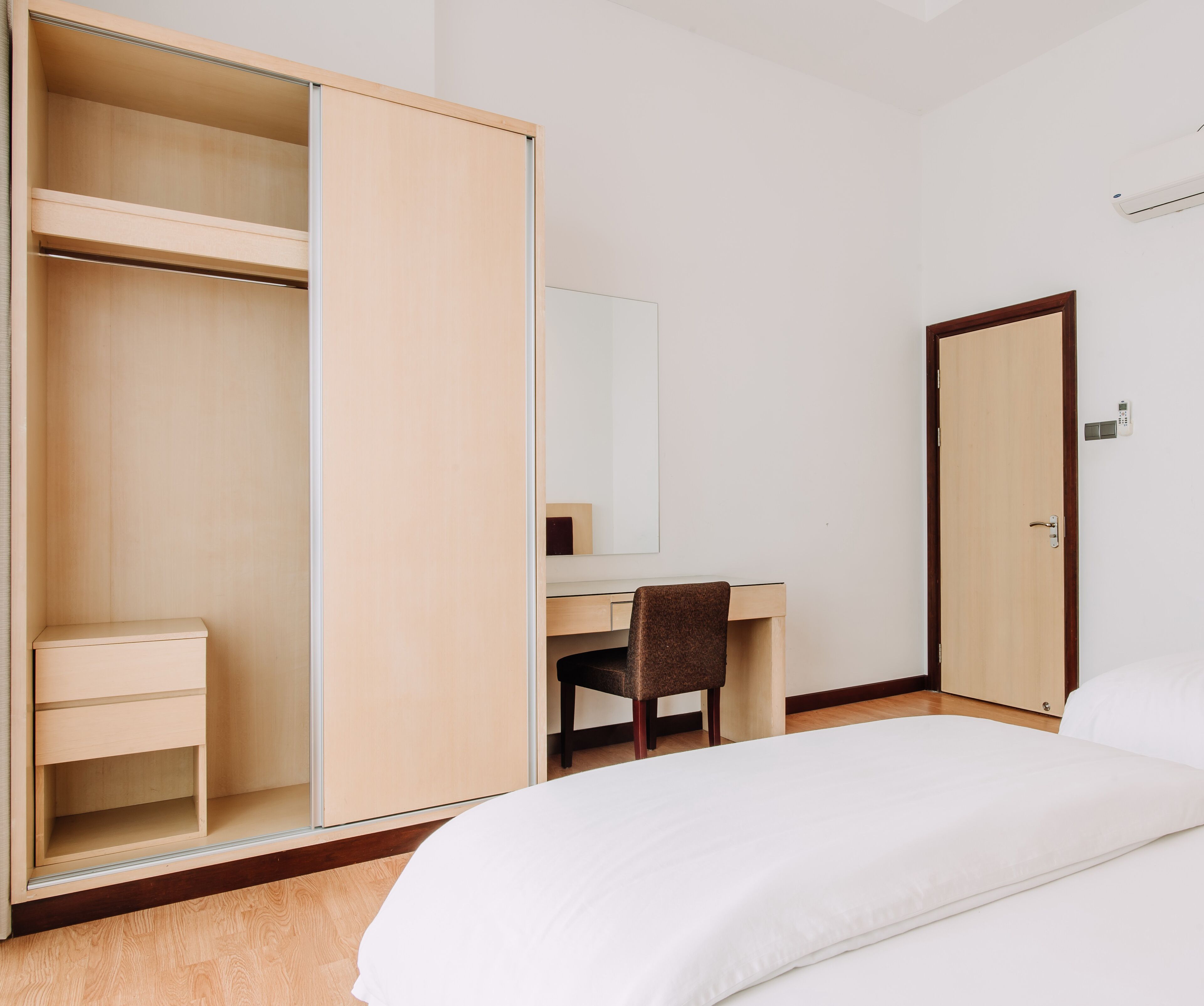 A bedroom with a bed, a desk, a chair, a wardrobe, and a door.