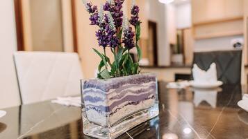 A glass vase with purple flowers on a reflective table in a modern interior setting.