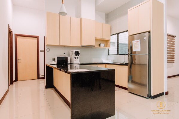 Una cocina moderna con una isla central, electrodomésticos de acero inoxidable y armarios de madera clara.