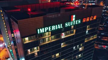 Un edificio de gran altura con el letrero "IMPERIAL SUITES", múltiples balcones y vistas del área urbana circundante.