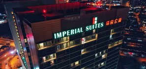 Un edificio de gran altura con el letrero "IMPERIAL SUITES", múltiples balcones y vistas del área urbana circundante.