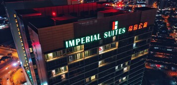 Un edificio de gran altura con el letrero "IMPERIAL SUITES", múltiples balcones y vistas del área urbana circundante.