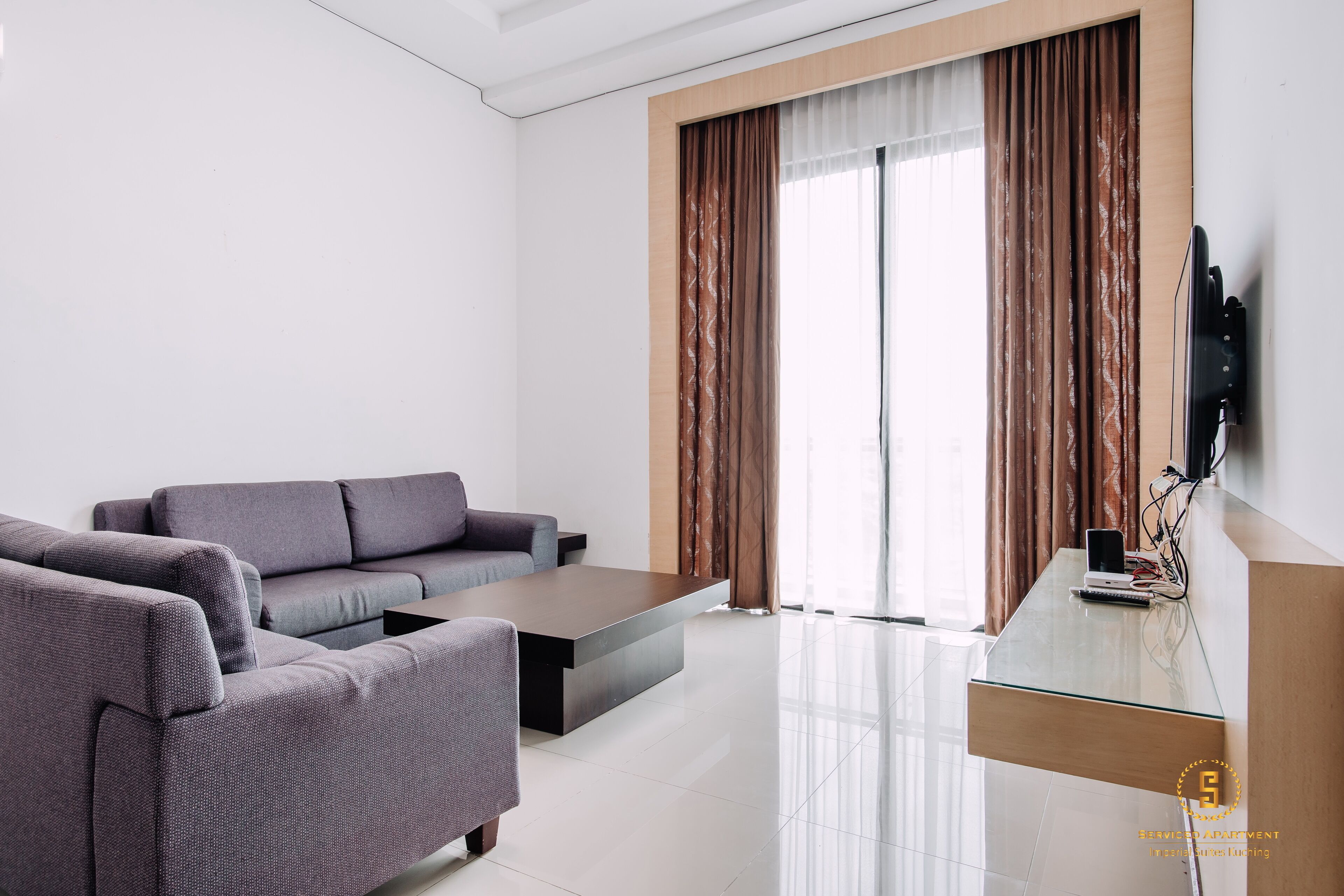 A modern living room with a sofa, coffee table, and a flat-screen TV mounted on the wall.