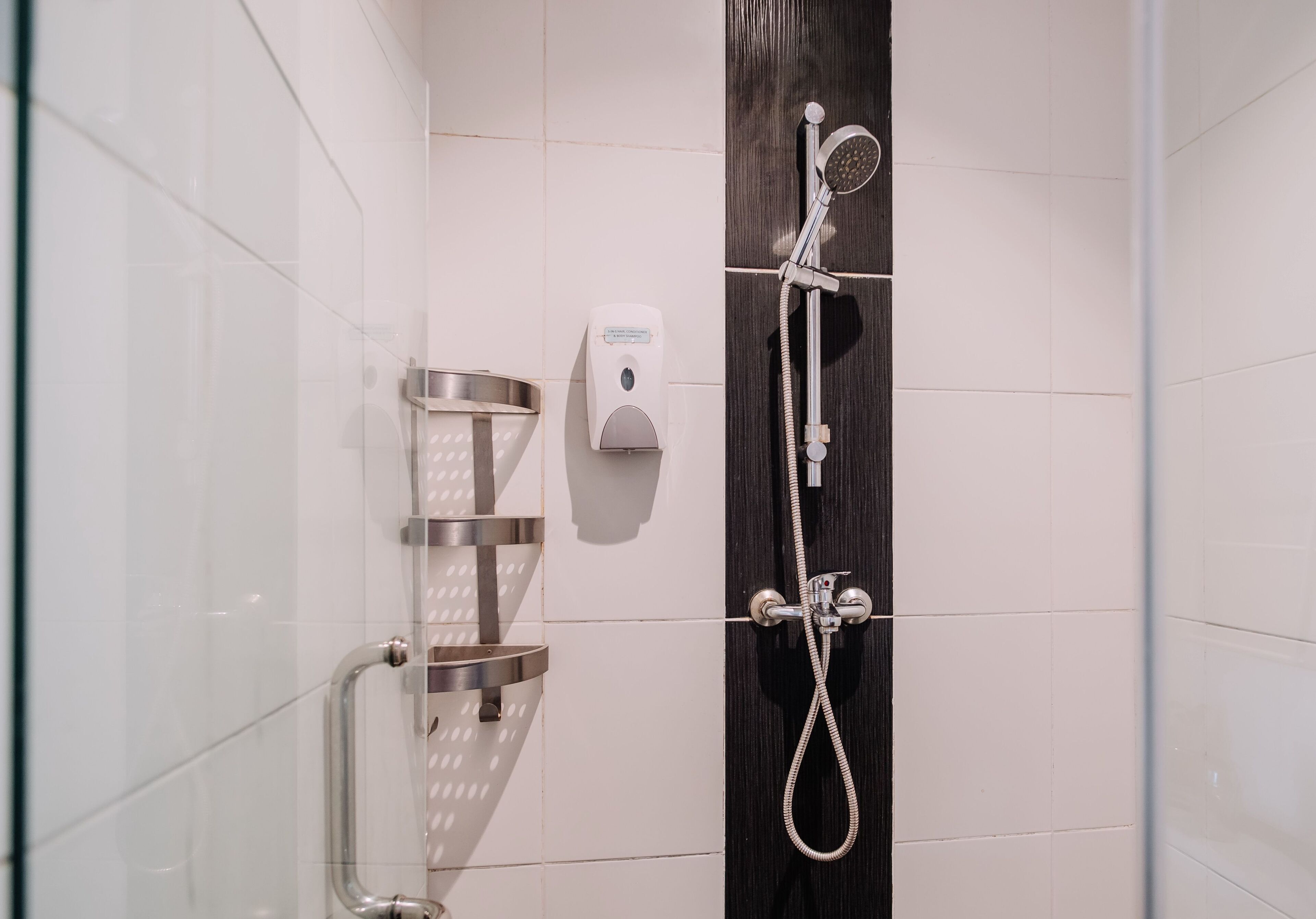 A modern shower with a handheld showerhead, a handheld soap dispenser, and a metal grab bar.