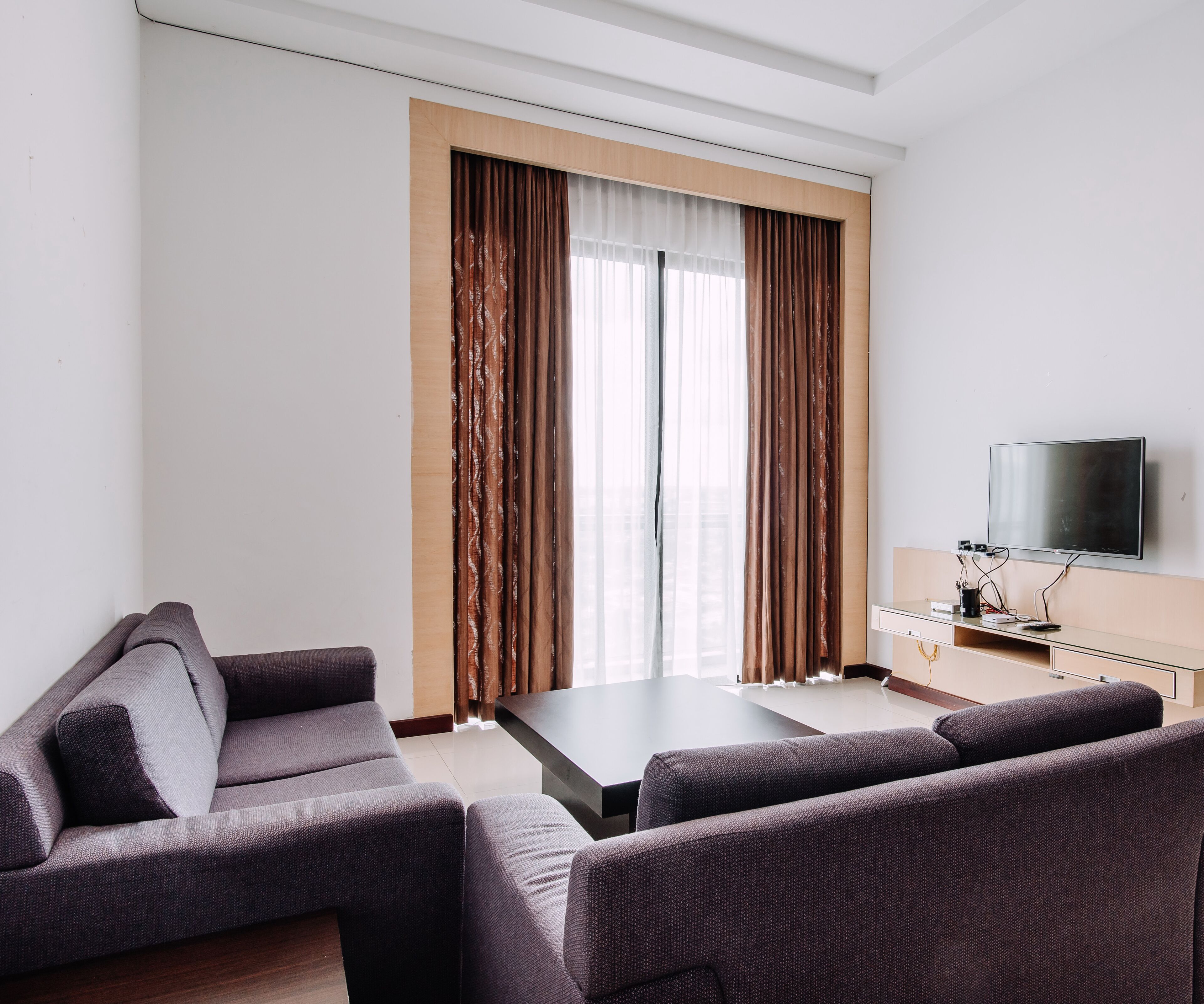 A modern living room with a sofa set, a coffee table, and a flat-screen TV mounted on the wall.