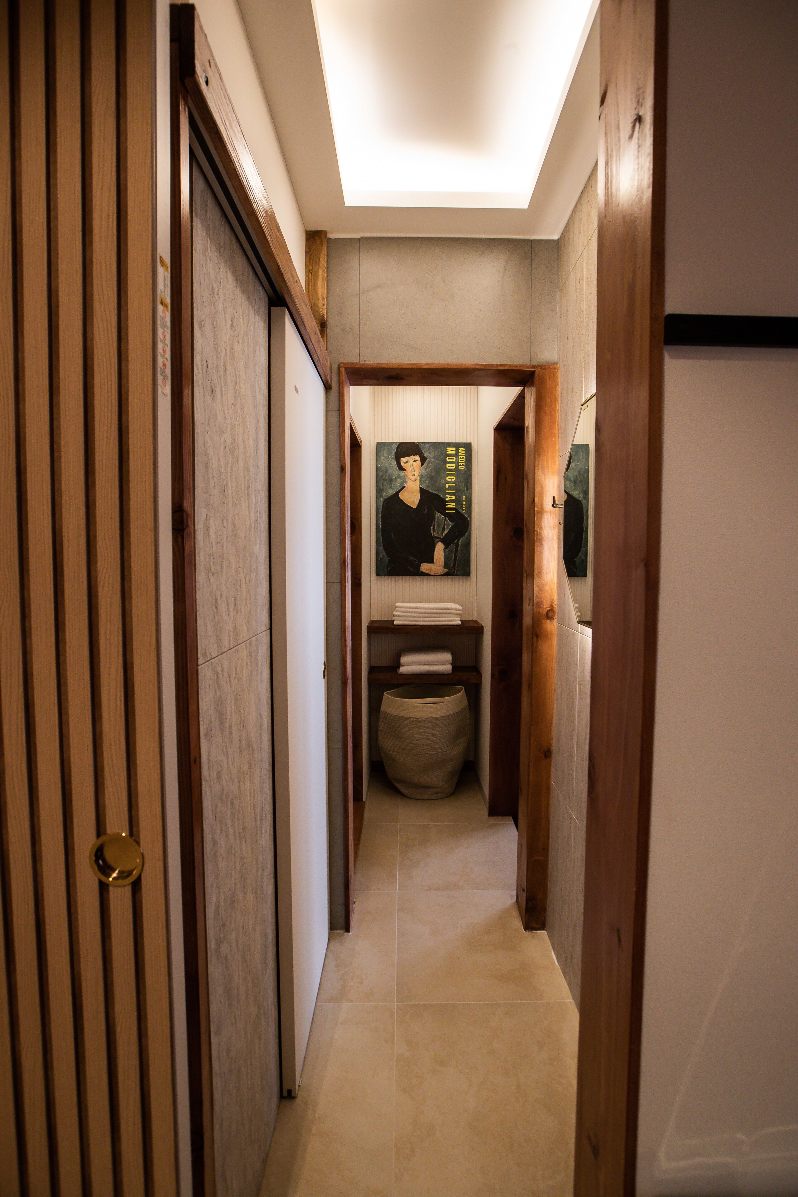 A narrow hallway with wooden paneling, a tiled floor, and a ceiling light.