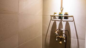 A modern shower with a handheld showerhead, a control panel, and a drain.