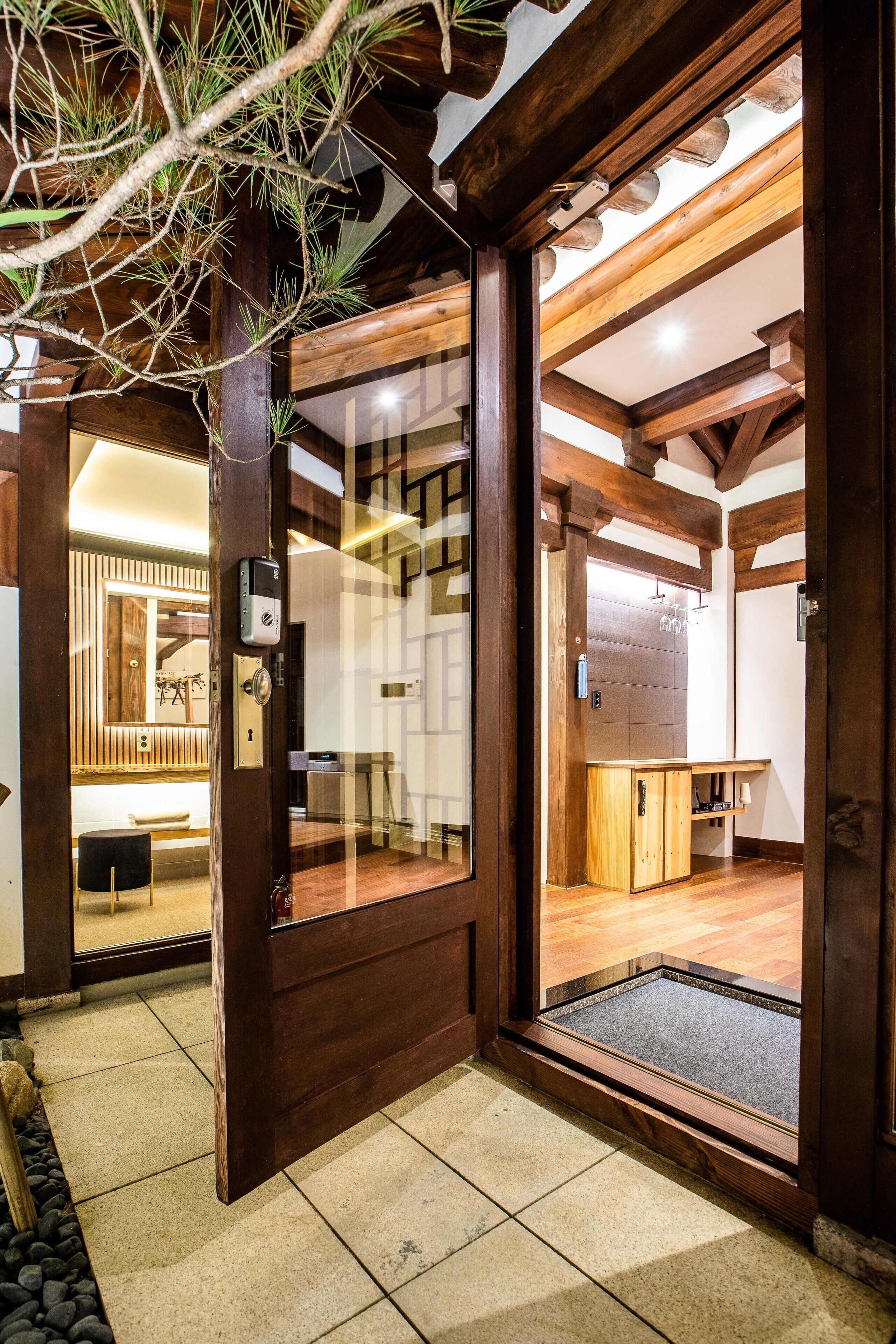A wooden interior with a glass door leading to a room with a bench and a wooden cabinet.