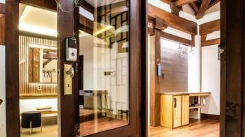A wooden interior with a glass door leading to a room with a bench and a wooden cabinet.