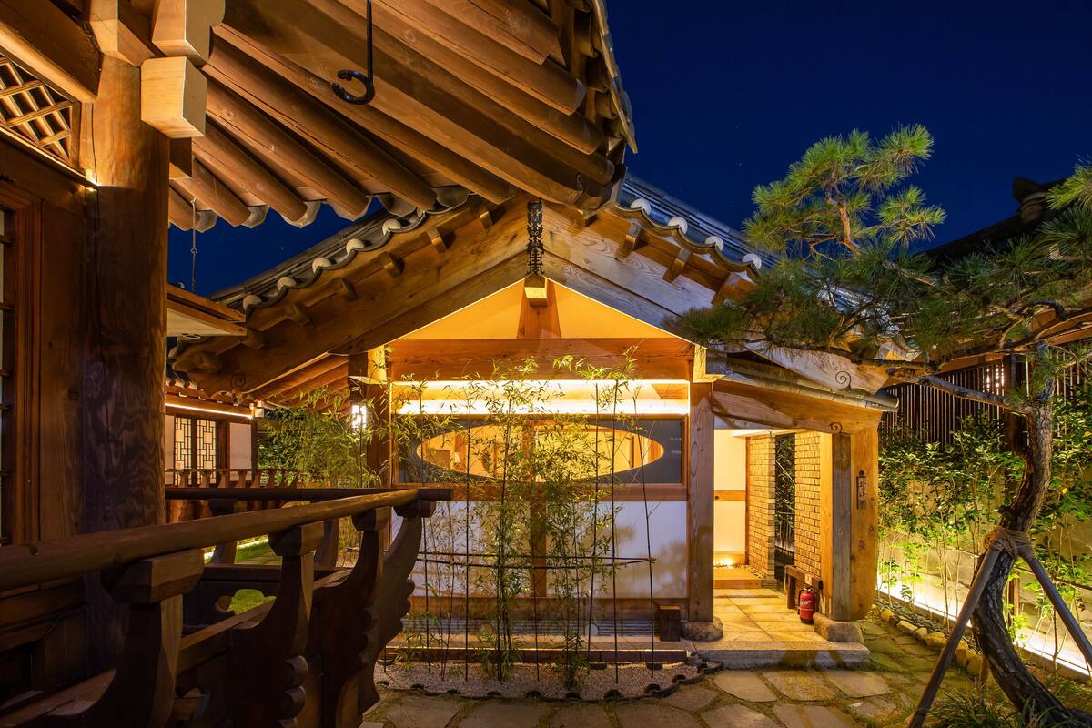 A traditional wooden building with a covered outdoor area, a bamboo plant, and a fire extinguisher.