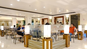 A restaurant with tables and chairs, a counter, and decorative elements. - De Luxe Hotel (Cagayan de Oro)