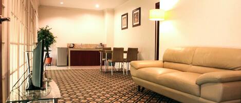 A hotel lobby with a patterned floor, a leather sofa, a glass coffee table, a reception desk, and framed pictures on the wall.
