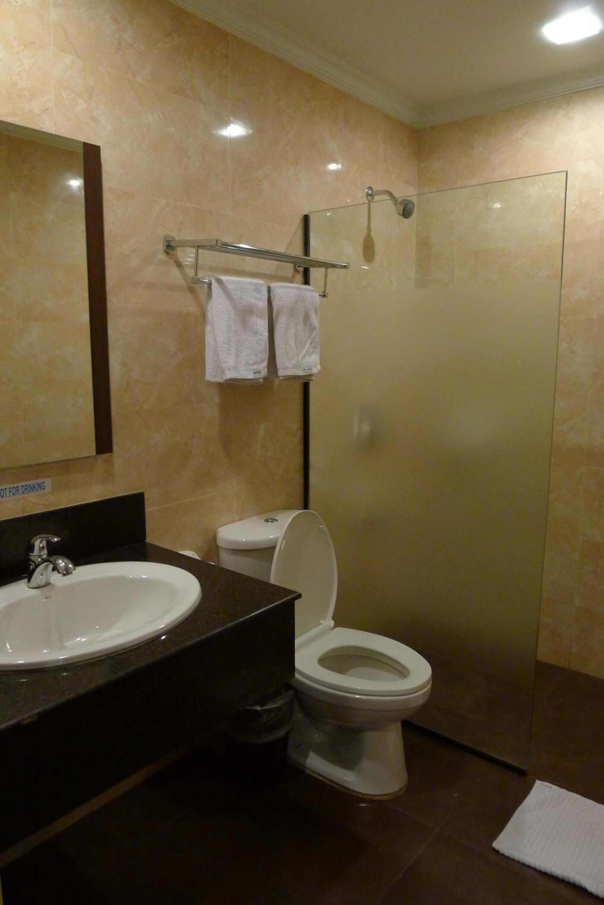 Un baño con lavabo, inodoro y cabina de ducha con mampara de vidrio.