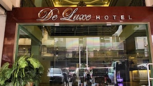 The entrance to De Luxe Hotel with a glass facade, a metal sign above the entrance, and a potted plant to the left. - De Luxe Hotel (Cagayan de Oro)