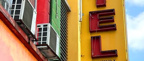 Un letrero vertical para un hotel con el nombre 'HOTEL' en letras rojas y negritas sobre un fondo amarillo.