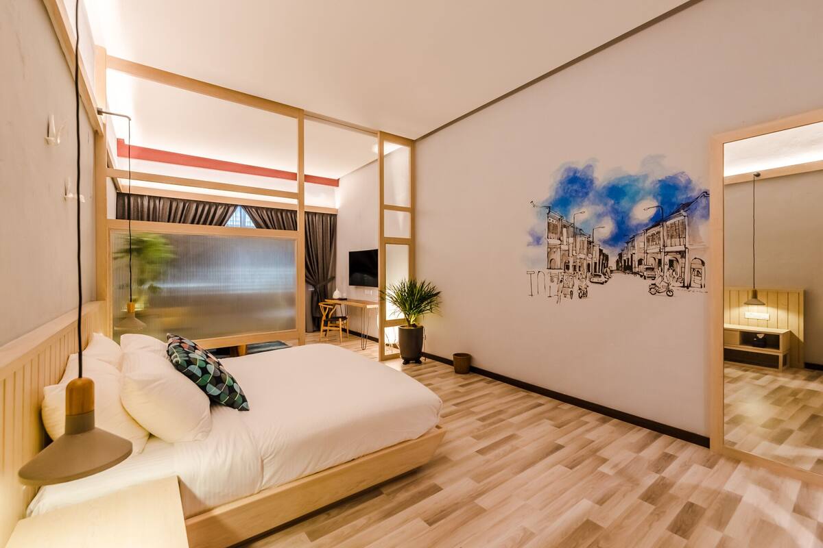 A modern hotel room with a bed, bedside table, and a large mirror.