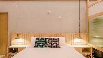 A hotel room with a wooden headboard, two bedside tables with lamps, a bed with white bedding, and two wall-mounted bird decorations.