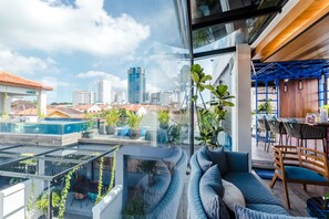 A modern rooftop terrace with a curved seating area, potted plants, and a view of the city skyline. - Tien Hotel (George Town)