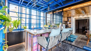 A modern kitchen with a bar area, large windows, and a blue ceiling. - Tien Hotel (George Town)