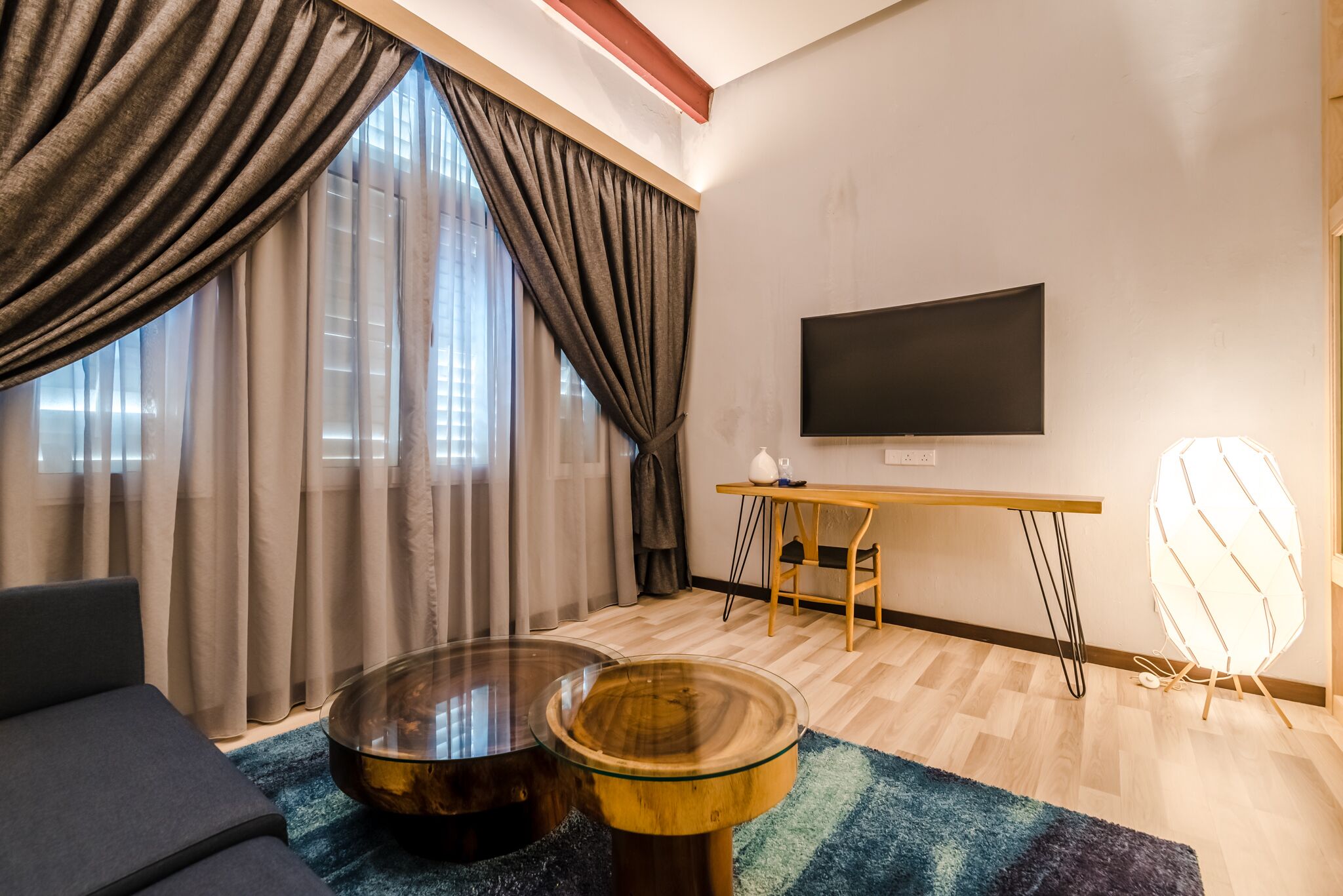 Een moderne woonkamer met een flatscreen televisie, een ronde glazen salontafel, een bank en een eethoek met een houten tafel en stoelen.