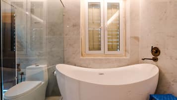 A bathroom with a bathtub, toilet, and glass shower enclosure.