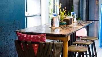Una cocina moderna con una mesa de madera, taburetes de bar, lámparas colgantes de cobre y vistas al exterior a través de amplios ventanales.
