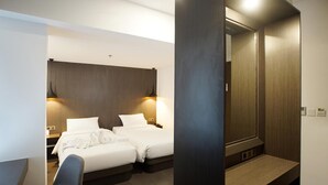 Une chambre d’hôtel moderne avec un grand lit, deux tables de chevet, une chaise et un grand miroir.
