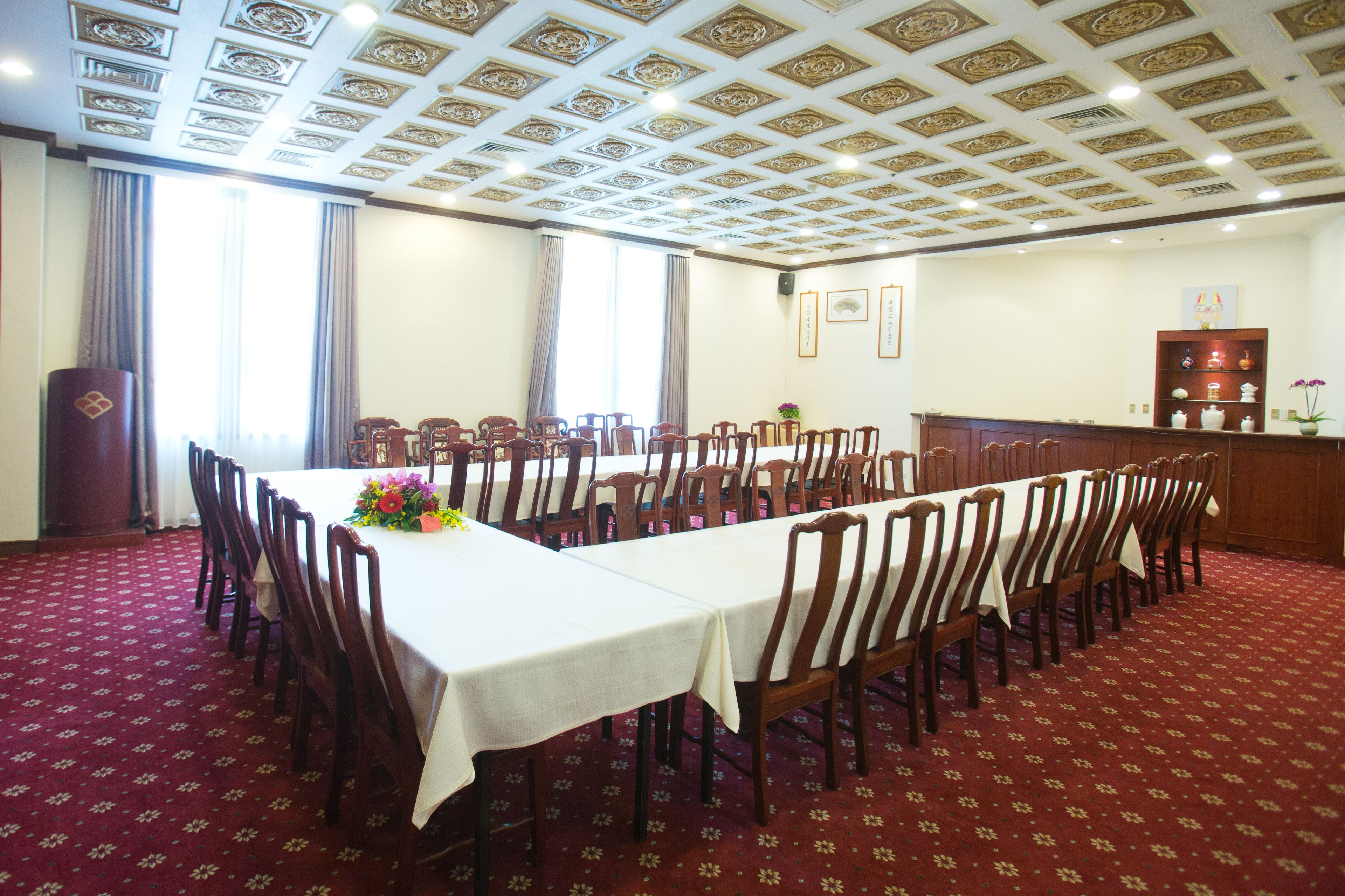 Un salón de conferencias con una larga mesa, sillas y un techo decorativo.