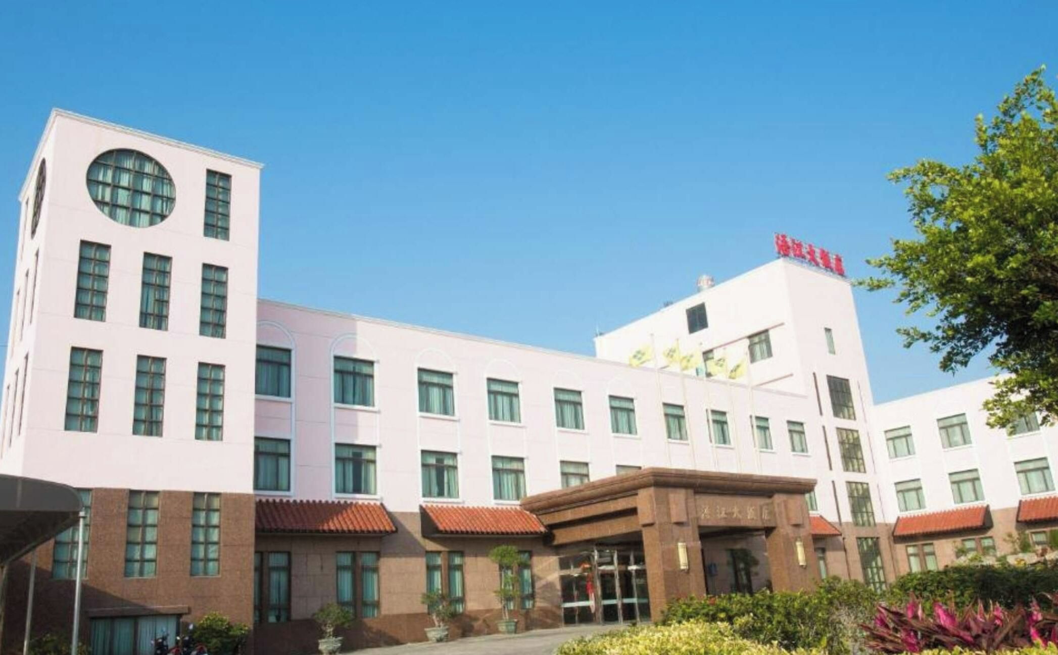 A modern hotel building with multiple floors, a central entrance, and a flag on top.