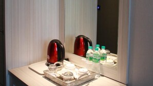 Un baño con espejo, lavamanos, tetera y artículos de aseo.
