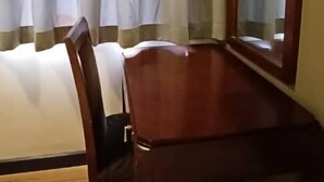Ein Zimmer mit einem Holztisch, einem einzelnen Stuhl und einem großen Spiegel an der Wand.
