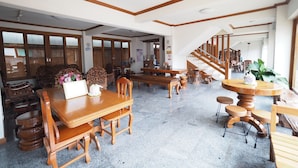 Une pièce spacieuse avec une grande table à manger en bois, plusieurs chaises et un escalier menant à un autre niveau.
