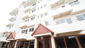 Un hôtel à plusieurs étages doté de balcons, de grandes fenêtres et d’une entrée principale en bois.