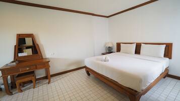 Un dormitorio con una cama de madera, un escritorio de madera con un espejo y una mesita de noche con una lámpara.