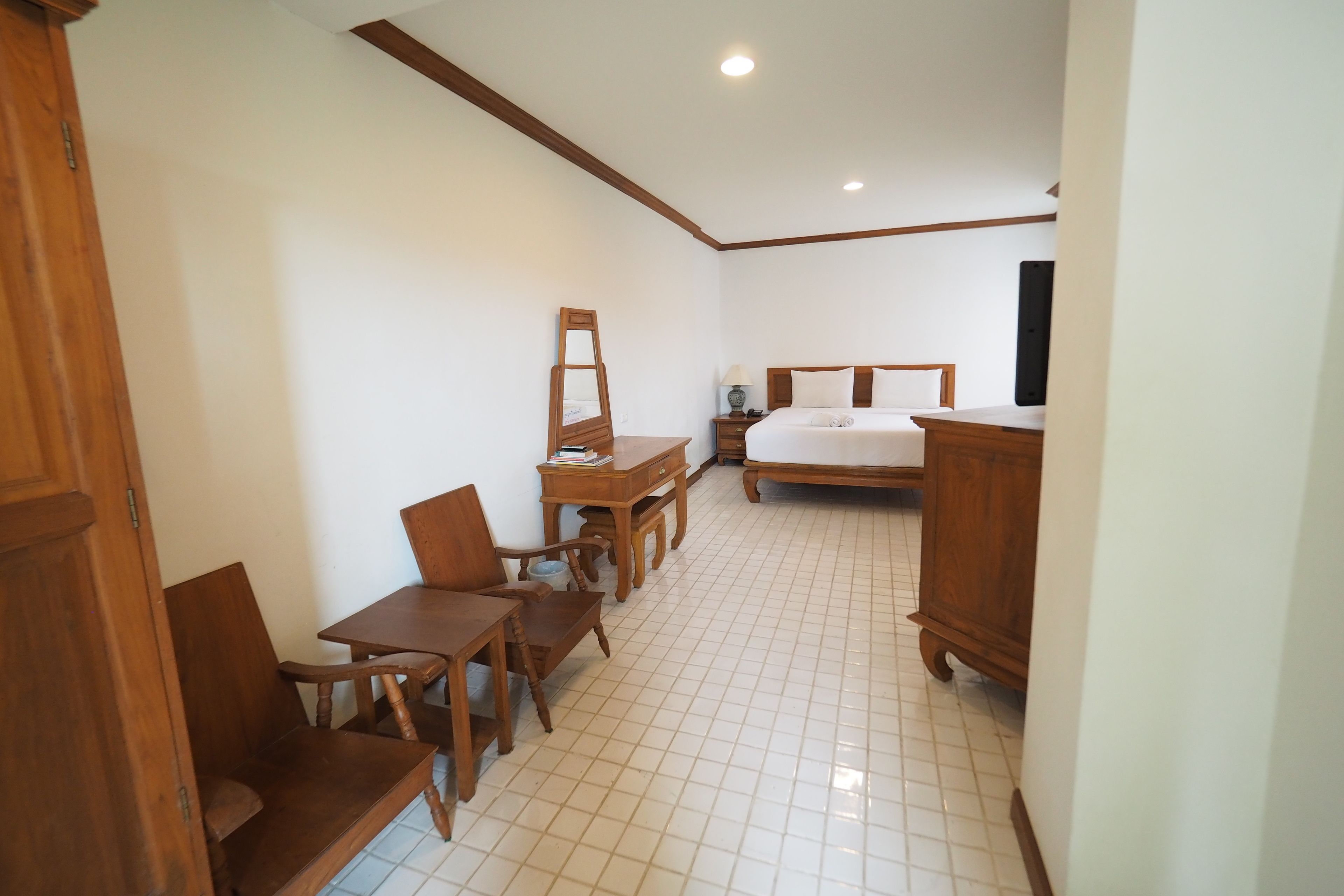 A bedroom with a bed, wooden furniture, a desk, and a chair.