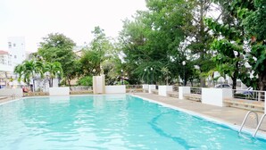 Una piscina rettangolare con acqua cristallina e blu, circondata da pareti bianche e un solarium piastrellato.