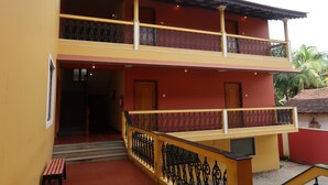 Un edificio de dos pisos con un balcón, una escalera y un banco.