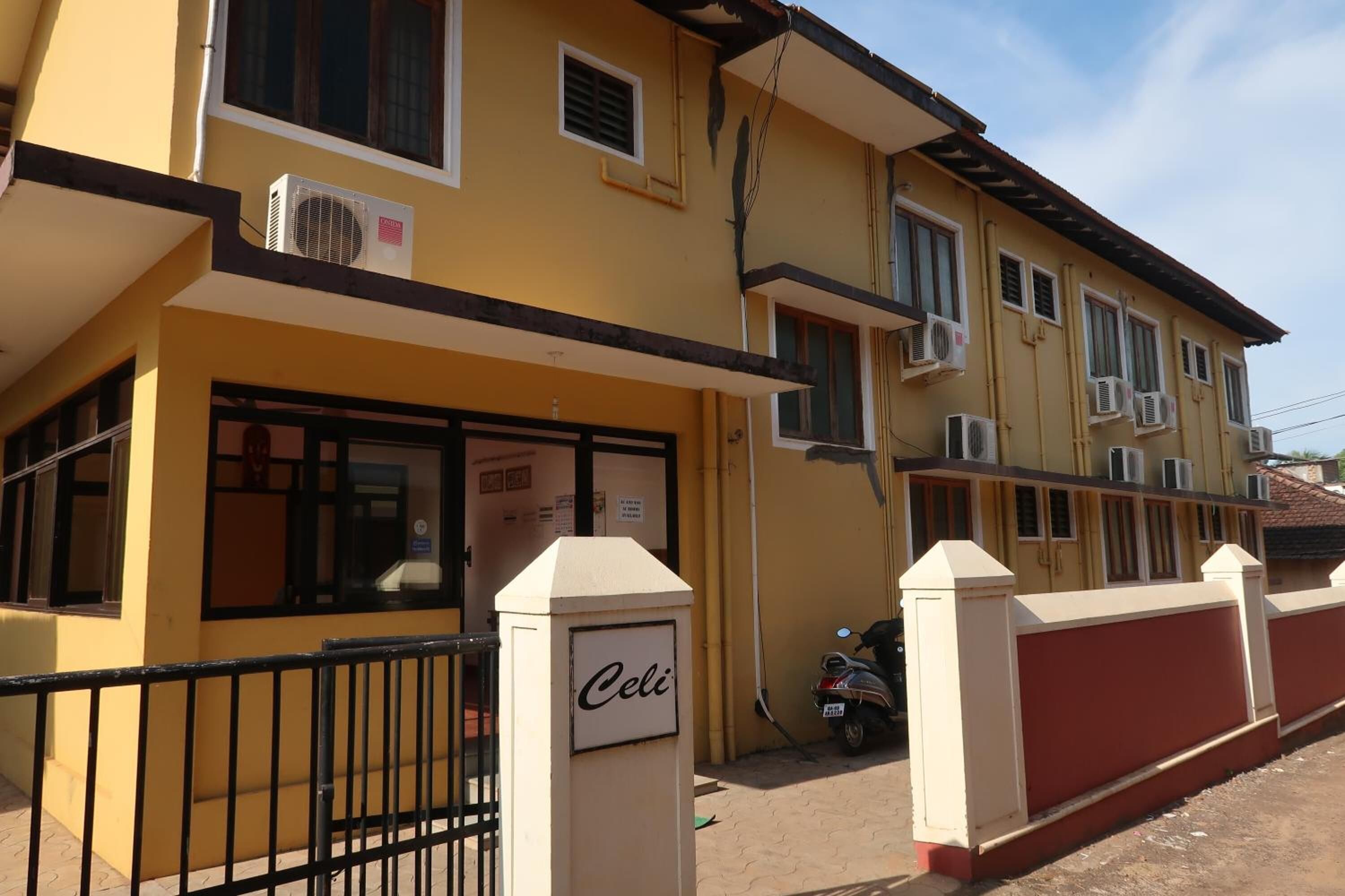 A yellow building with multiple air conditioning units, a gated entrance, and a sign that reads "Celi".