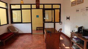 Una habitación con un escritorio de madera, una silla, un banco y una estantería con libros y una computadora.