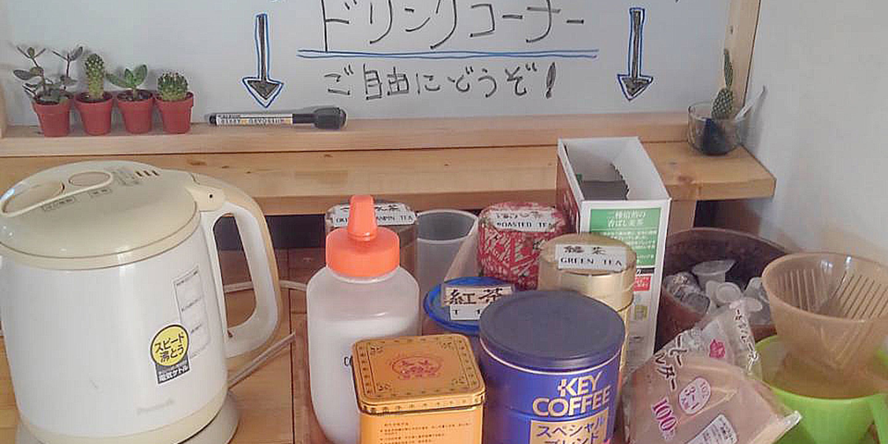 A kitchen counter with various items including a coffee maker, a water jug, and containers of coffee and tea.