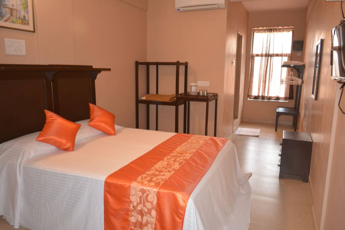 A hotel room with a bed, a chair, a desk, and a television.