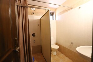 A small, compact bathroom with a toilet, a sink, and a shower stall. - Dimar Beach Hotel (Calangute)