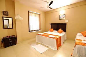 A hotel room with two beds, a ceiling fan, a window with curtains, a dresser, and a small rug. - Dimar Beach Hotel (Calangute)